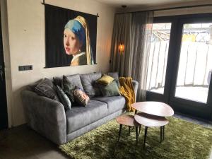 BNB DREAMS في Vorstenbosch: غرفة معيشة بها أريكة و لوحة لسيدة
