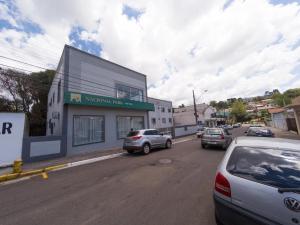 a street with cars parked in front of a building at Nacional Park Hotel Lages in Lages