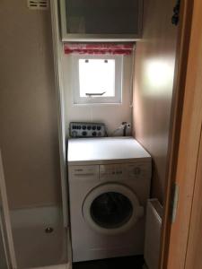 a small bathroom with a washing machine and a window at Chalet 4-5 Pers in Epe F16 Van alle gemakken voorzien Max aantal volwassenen is 4 in Epe