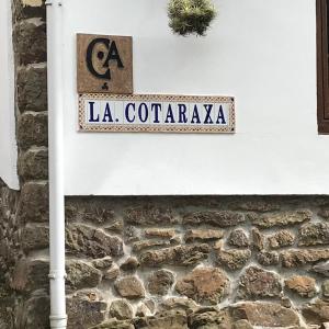 un cartello stradale sul lato di un muro di pietra di LA COTARAXA a Piloña