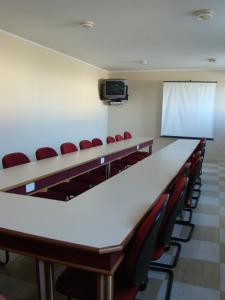 a conference room with a long table and red chairs at Blanco Palace Hotel in São José dos Campos