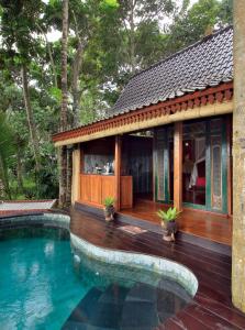 a house with a swimming pool in front of it at Masakali Retreat in Ubud