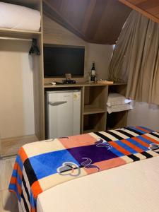 a room with a bed and a desk with a television at Pousada Schmitz in Canela