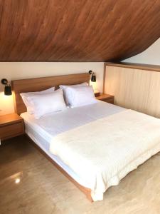 sypialnia z dużym białym łóżkiem i drewnianym sufitem w obiekcie Vimala Hills Villa 4 Bedroom with Mountain View w mieście Bogor