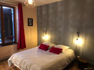 ein Schlafzimmer mit einem Bett mit zwei roten Kissen in der Unterkunft Ancienne Gare du Val des Bois in Warmeriville