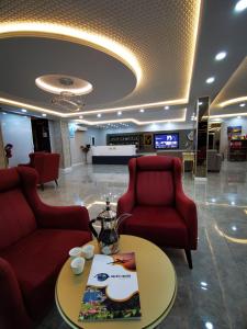 eine Lobby mit zwei roten Stühlen und einem Tisch in einem Gebäude in der Unterkunft Aysa Suite in Trabzon
