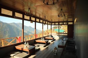 a group of tables in a room with mountains in the background at Odin Hostel Shoja in Shoja