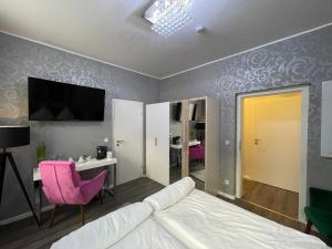 a bedroom with a bed and a desk and a tv at Boutiquehotel Mason in Altenburg