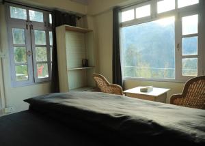 a bedroom with two windows and a bed with chairs at Odin Hostel Shoja in Shoja
