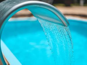 a pool with blue water pouring from a hose at Pousada Flor de Ipe in São Bento do Sapucaí