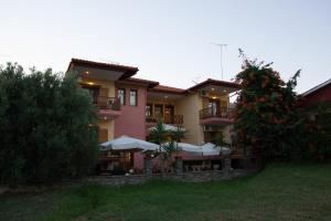 a building with tables and umbrellas in front of it at Hotel Ismini in Ammouliani