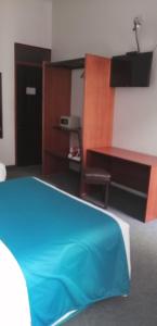 普諾的住宿－科羅尼爾廣場酒店，一间卧室配有蓝色的床和一张书桌