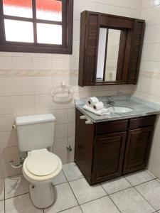 a bathroom with a toilet and a sink and a mirror at Hotel Praia Bonita in Capão da Canoa