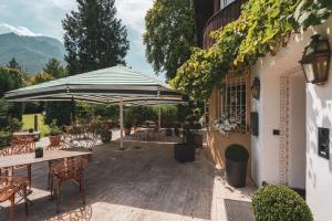 a patio with an umbrella and tables and chairs at Villa Sonnenhof Boutique-Hotel in Bad Reichenhall