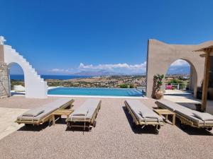 une terrasse avec 2 chaises longues et une piscine dans l'établissement Villa Grabella-Amazing sea view and swimming pool, à Pitsidia