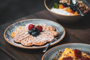 a plate of pancakes with berries and a bowl of cereal at Villa Sonnenhof Boutique-Hotel in Bad Reichenhall