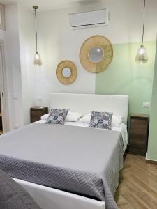 a bedroom with a large white bed with two mirrors at I Faraglioni Comfort Rooms in Terrasini