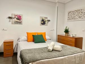 um quarto com uma cama com almofadas laranja e verde em Lovely holidays em Benidorm