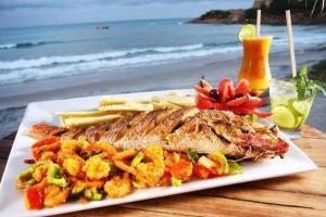 a plate of fish and chips on a table next to the beach at Oceano Azul Hospedagens a 50 M DA ORLA-Passarela do Caranguejo in Aracaju