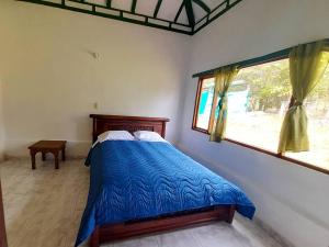 sypialnia z łóżkiem z niebieską kołdrą i oknem w obiekcie CABAÑA VILLA LUISA de LEYVA w mieście Villa de Leyva