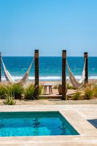a resort with a swimming pool and hammocks and the beach at Norte Suites Boutique in Los Órganos