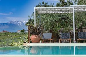 uma piscina com cadeiras e uma pérgola e montanhas em Borgo Baccile by Vini Fantini em Crecchio