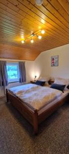 a large bed in a bedroom with a wooden ceiling at Ferienwohnung mit Pool in Nordleda