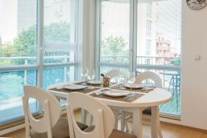 a white dining room with a table and chairs and windows at Kabakum Apartments in Golden Sands