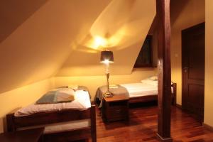 a attic room with two beds and a lamp at Pokoje Galeria Brama in Kazimierz Dolny