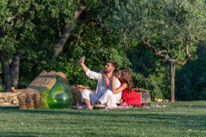 Ein Mann und eine Frau sitzen auf dem Gras in der Unterkunft Borgo Baccile by Vini Fantini in Crecchio