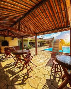 a patio with tables and chairs under a wooden pergola at Pousada Rural Estação Verde in Bonito