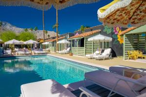 a pool at a resort with chairs and umbrellas at Fleur Noire Hotel - 21 and Over in Palm Springs