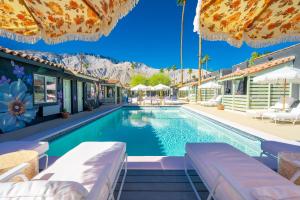 a swimming pool with chairs and umbrellas at Fleur Noire Hotel - 21 and Over in Palm Springs