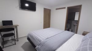 a bedroom with a bed and a desk and a television at Hotel Andina Blue in Funza