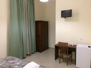 um pequeno quarto com uma secretária e uma televisão em Albergo Enrica em Roma