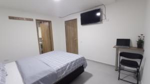 a bedroom with a bed and a chair and a flat screen tv at Hotel Andina Blue in Funza +31 photos