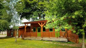 a wooden cabin with a large porch in a yard at Marcassie Farm Lodges - Birch Studio in Forres