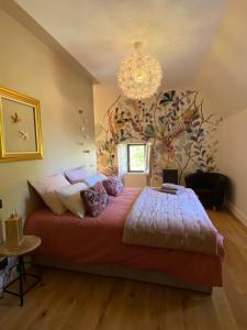 um quarto com uma cama grande e um lustre em Domaine de la Bigottière em Montigné-le-Brillant