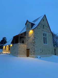 Una vieja iglesia de piedra en la nieve por la noche en Domaine de la Bigottière, en Montigné-le-Brillant