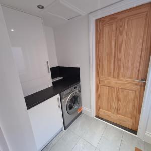 uma cozinha com uma máquina de lavar roupa e uma porta de madeira em Kelvin Suite em Jesmond