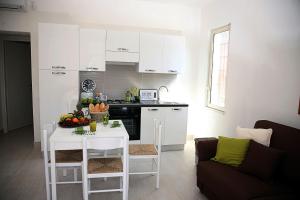 een keuken met een witte tafel en een witte tafel en stoelen bij Car'Loft beachside in Cagliari