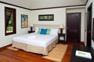 a bedroom with a bed with white sheets and blue pillows at Santosha Barbados in Saint Andrew