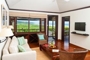 a living room with a couch and a table and a television at Santosha Barbados in Saint Andrew