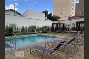 a swimming pool with lounge chairs next to a building at Maravilhoso Studio Flat Apto no Bosque - Campinas in Campinas