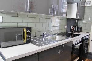 a kitchen with a sink and a microwave at Jerry's Apartment Blue in Kent