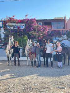 a group of people posing for a picture with horses at dar boujdaa in Sidi Kaouki