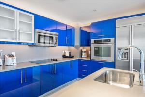 uma cozinha azul com electrodomésticos de aço inoxidável e armários azuis em W Residences 2 Bedroom Suite condo em Fort Lauderdale