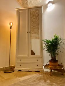 a large white cabinet in a room with a potted plant at Dimora Le Volte Ostuni in Ostuni