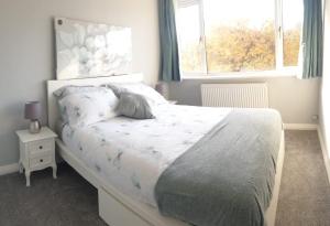 a bedroom with a white bed with a window at Cosy 3 bedroom residential house, private garden, 30 minutes from Alton Towers, 5 minute walk to Trentham Gardens. in Stoke on Trent