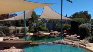 a swimming pool with an umbrella in a garden at Pomonal Cottages Grampians in Halls Gap +30 photos